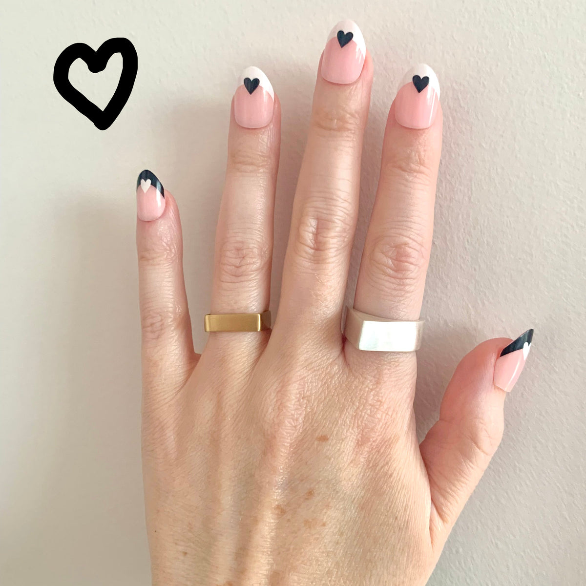 Pyramid Ring in recycled sterling silver and Square Band Ring in eco-friendly brass, worn on hand with black heart nail art – Black Heart Jewelers