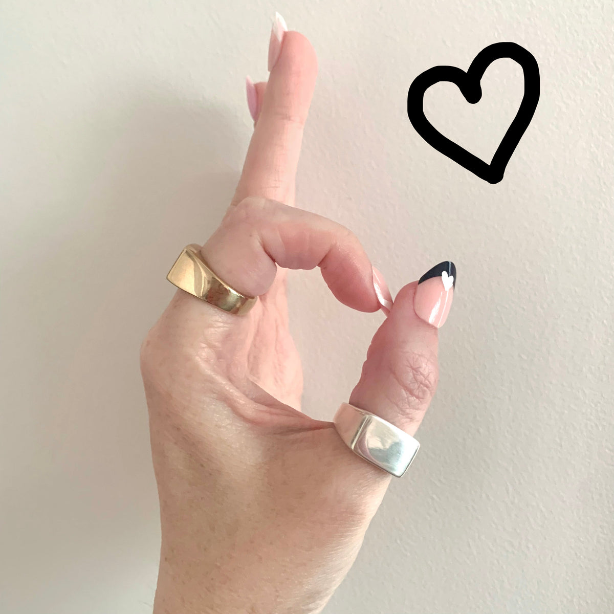 Signet Ring in eco-friendly brass and recycled sterling silver, worn on hand making OK gesture with drawn heart graphic – Black Heart Jewelers